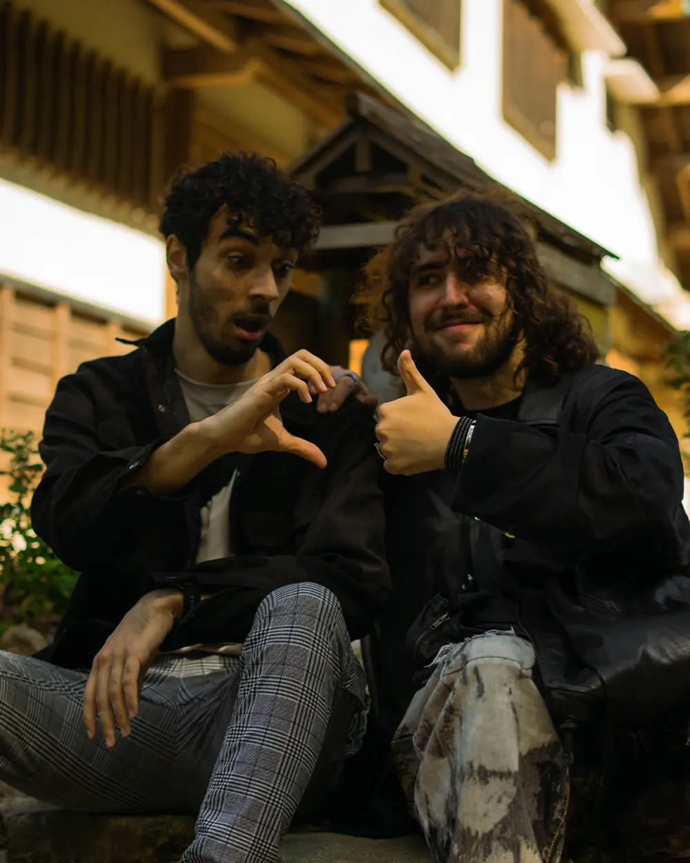 Two persons sitting in front of Jigokudani Monkey Park inn hand gestures Nagano, Japan